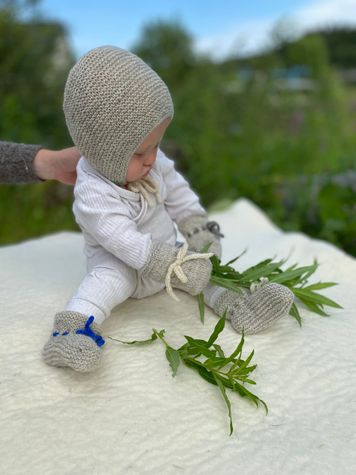 Baby med ullsokker, votter og lue