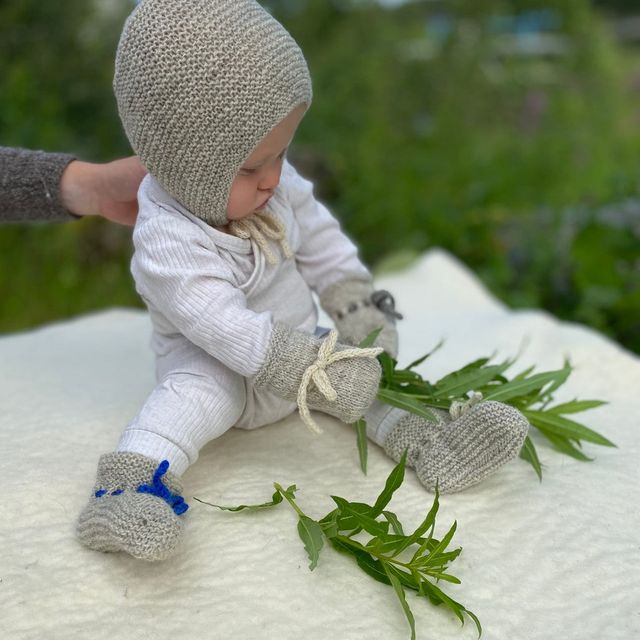 Baby med ullsokker, votter og lue