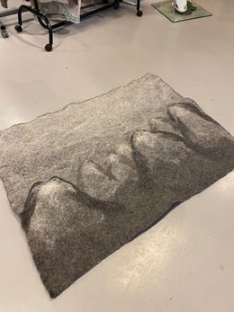 Grått tova teppe med mønster av fjell