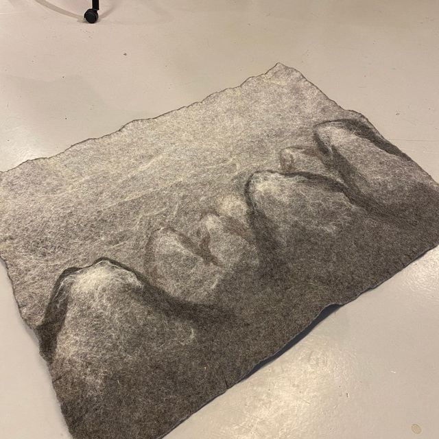 Grått tova teppe med mønster av fjell