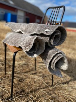 Tre sammenrullede ttova tepper på en stol