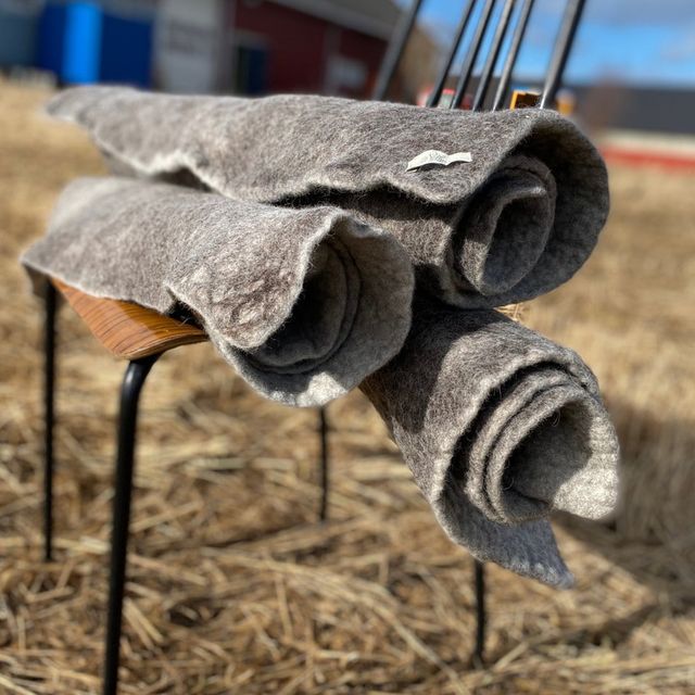 Tre sammenrullede ttova tepper på en stol