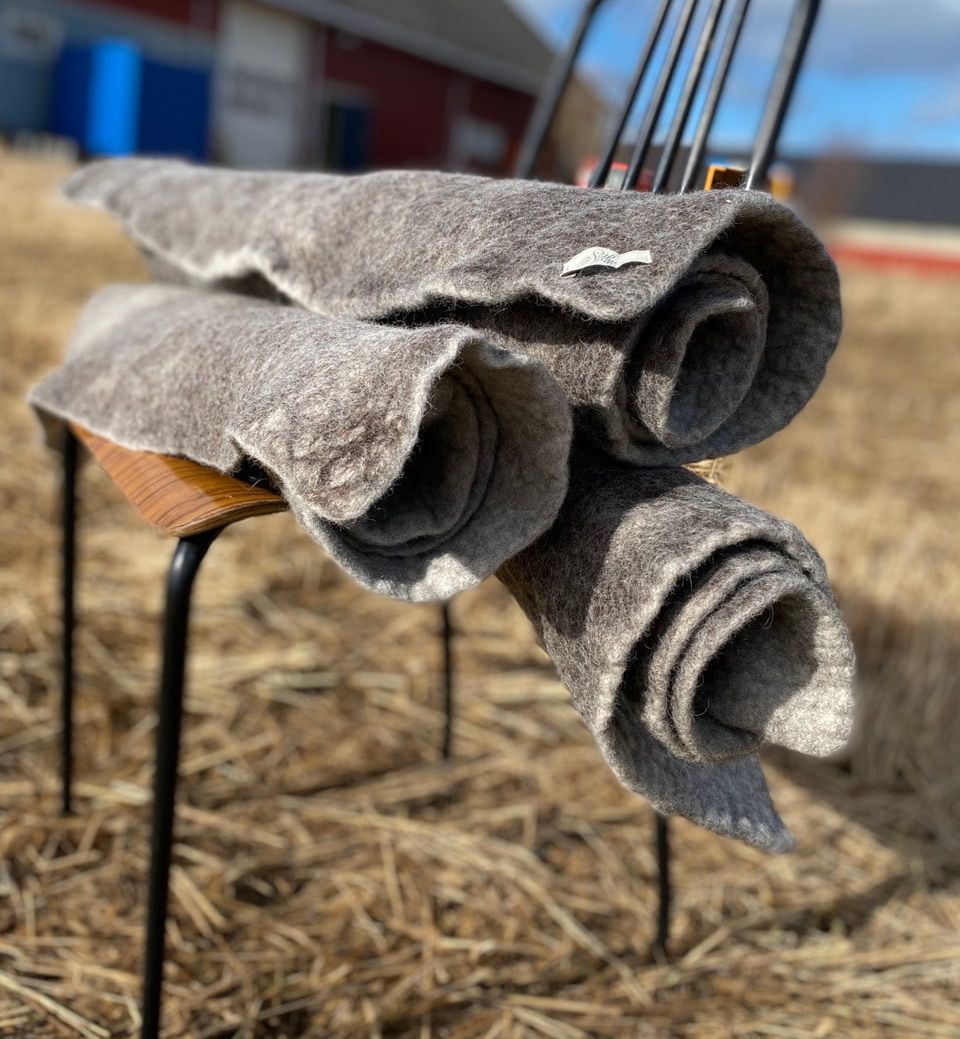 Tre sammenrullede ttova tepper på en stol